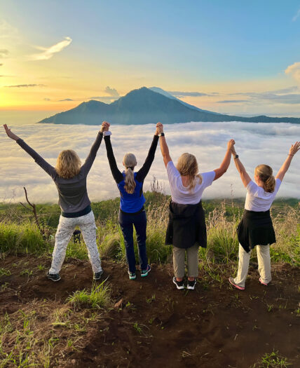 Mount Batur sunrise with women holding hands up