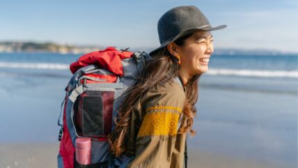 Asian woman wearing backpack on beach